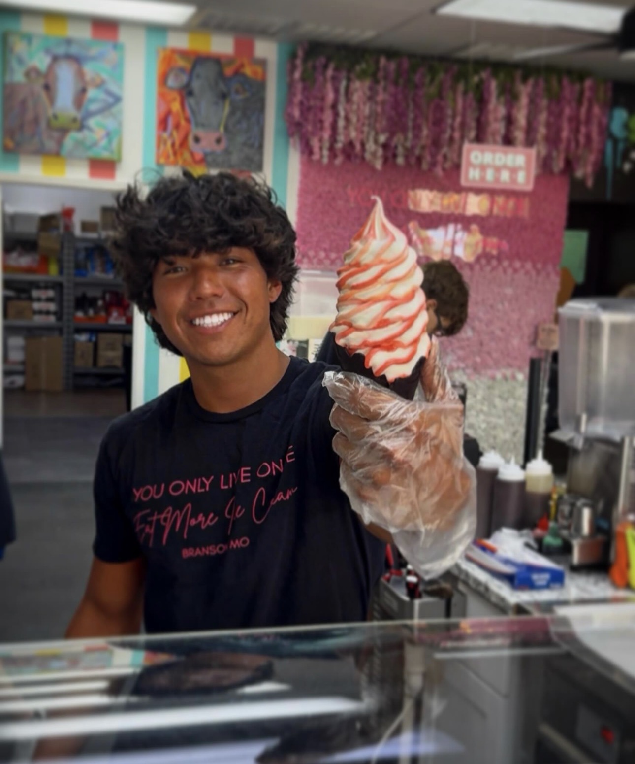 YOLO team member serving a strawberry-swirl flavor burst soft serve in a chocolate cone